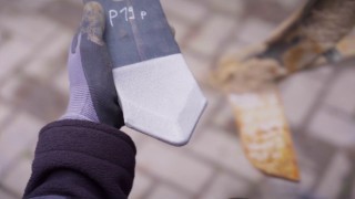 Photo of a hand wearing a protective glove holding a thermally coated plowshare tip.