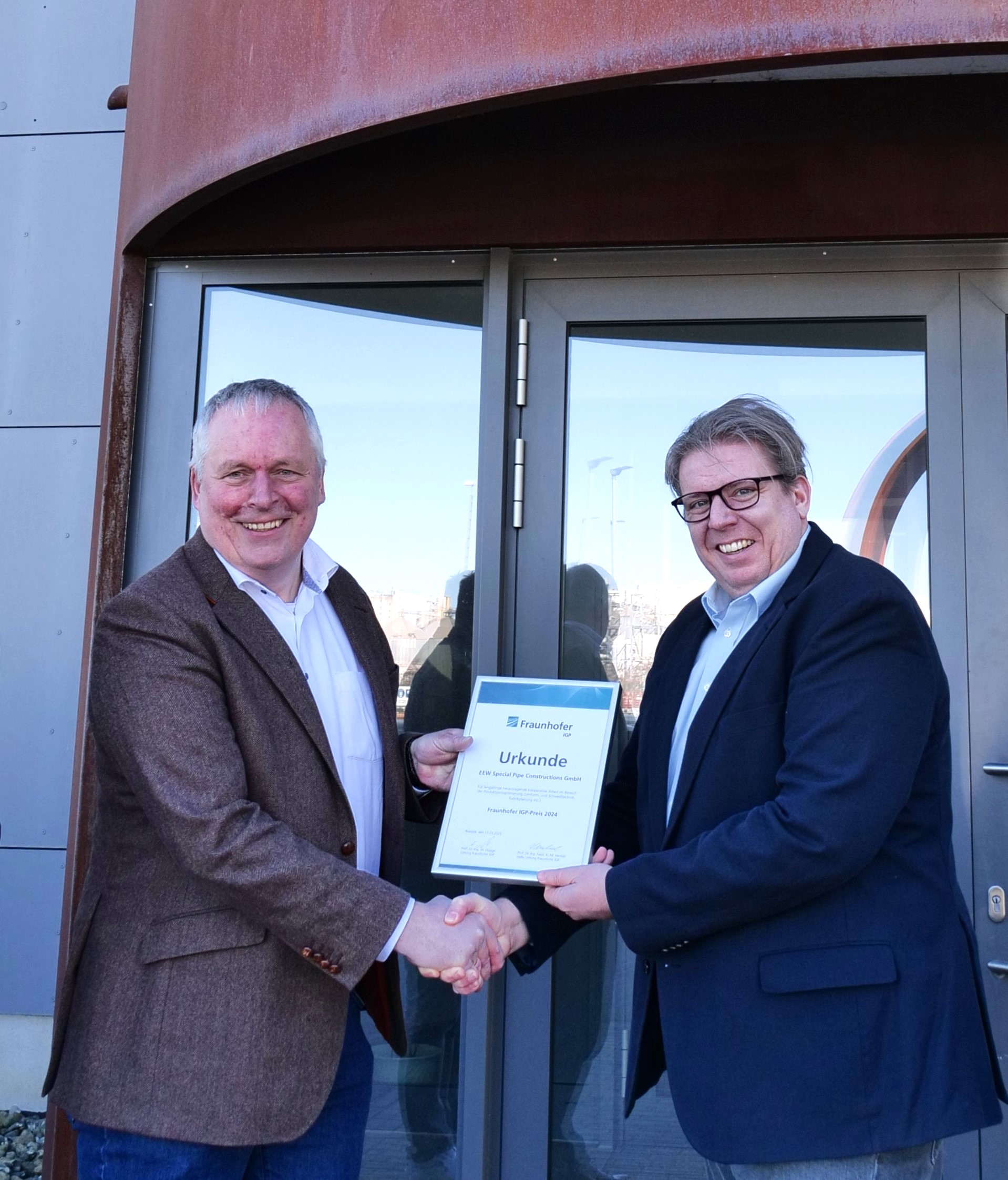 Prof. Flügge (Fraunhofer IGP) shaking Andreas Dörge's (EEW Special Pipe Constructions GmbH) hand and presents him with the diploma for the Fraunhofer IGP Award.