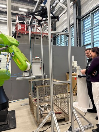 Photo of a researcher and a visitor looking at the green Fanuc robot arm at Fraunhofer IGP.